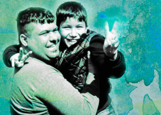 A smiling father, holding his happy son who is doing the peace symbol with both his hands